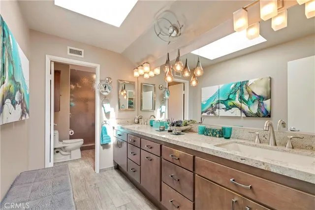 a spacious bathroom with a granite countertop sink a toilet a mirror and a shower