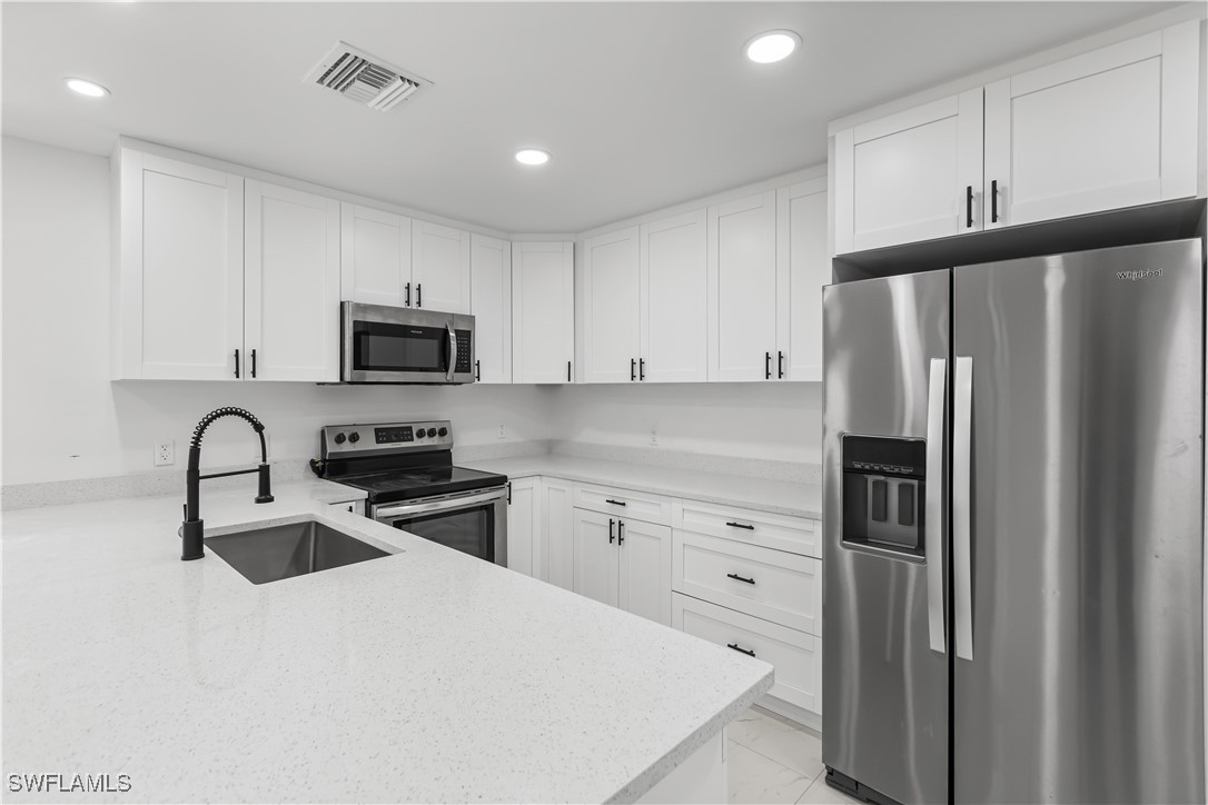 100 Wyoming Road Lehigh Acres, FL 33936 - Photo 12 of 38 a kitchen with a refrigerator sink and white cabinets