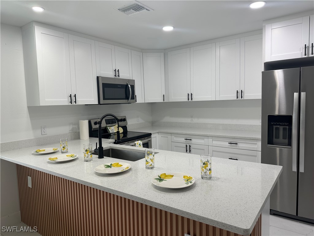100 Wyoming Road Lehigh Acres, FL 33936 - Photo 5 of 38 a kitchen with a sink a stove and refrigerator