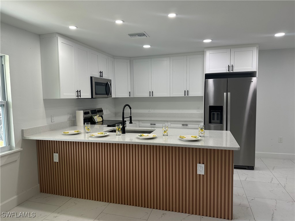 100 Wyoming Road Lehigh Acres, FL 33936 - Photo 6 of 38 a kitchen with stainless steel appliances granite countertop a sink dishwasher a refrigerator and a microwave with wooden cabinets
