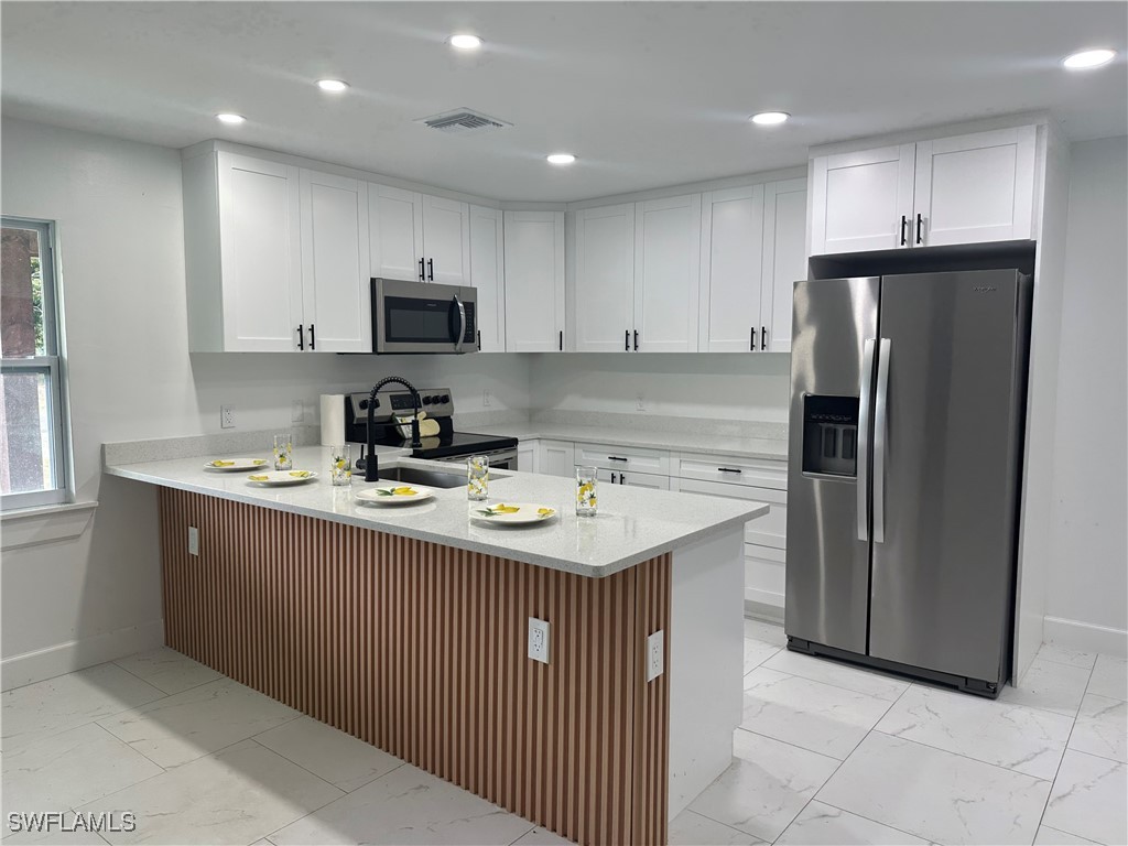 100 Wyoming Road Lehigh Acres, FL 33936 - Photo 7 of 38 a kitchen with stainless steel appliances granite countertop a refrigerator a sink a stove a microwave and a refrigerator