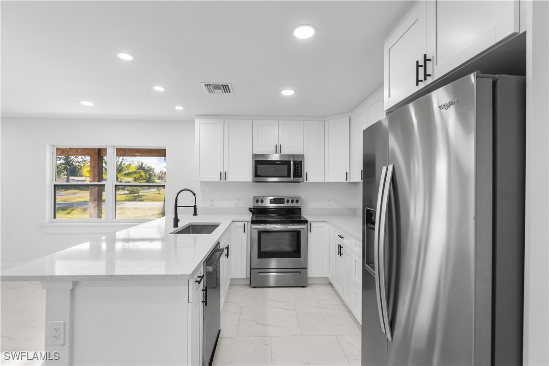 100 Wyoming Road Lehigh Acres, FL 33936 - Photo 8 of 38 a kitchen with stainless steel appliances granite countertop a refrigerator a sink a stove and a refrigerator with wooden floor
