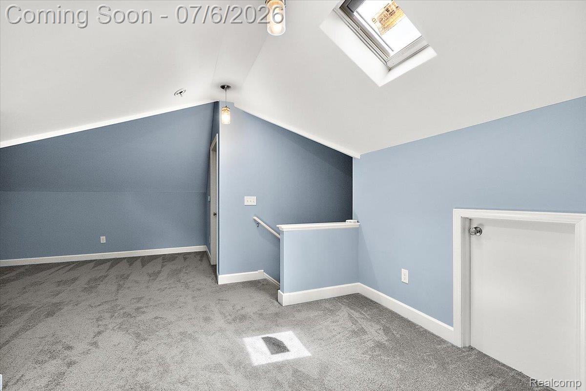 1051 Devonshire Road Grosse Pointe, MI 48230 - Photo 64 of 98 Attic space featuring vaulted ceilings, light blue wall paint, gray carpeting, a skylight, and contemporary pendant lighting
