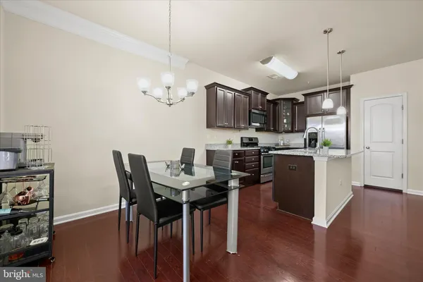 a kitchen with stainless steel appliances granite countertop a stove top oven a sink dishwasher a dining table and chairs with wooden floor