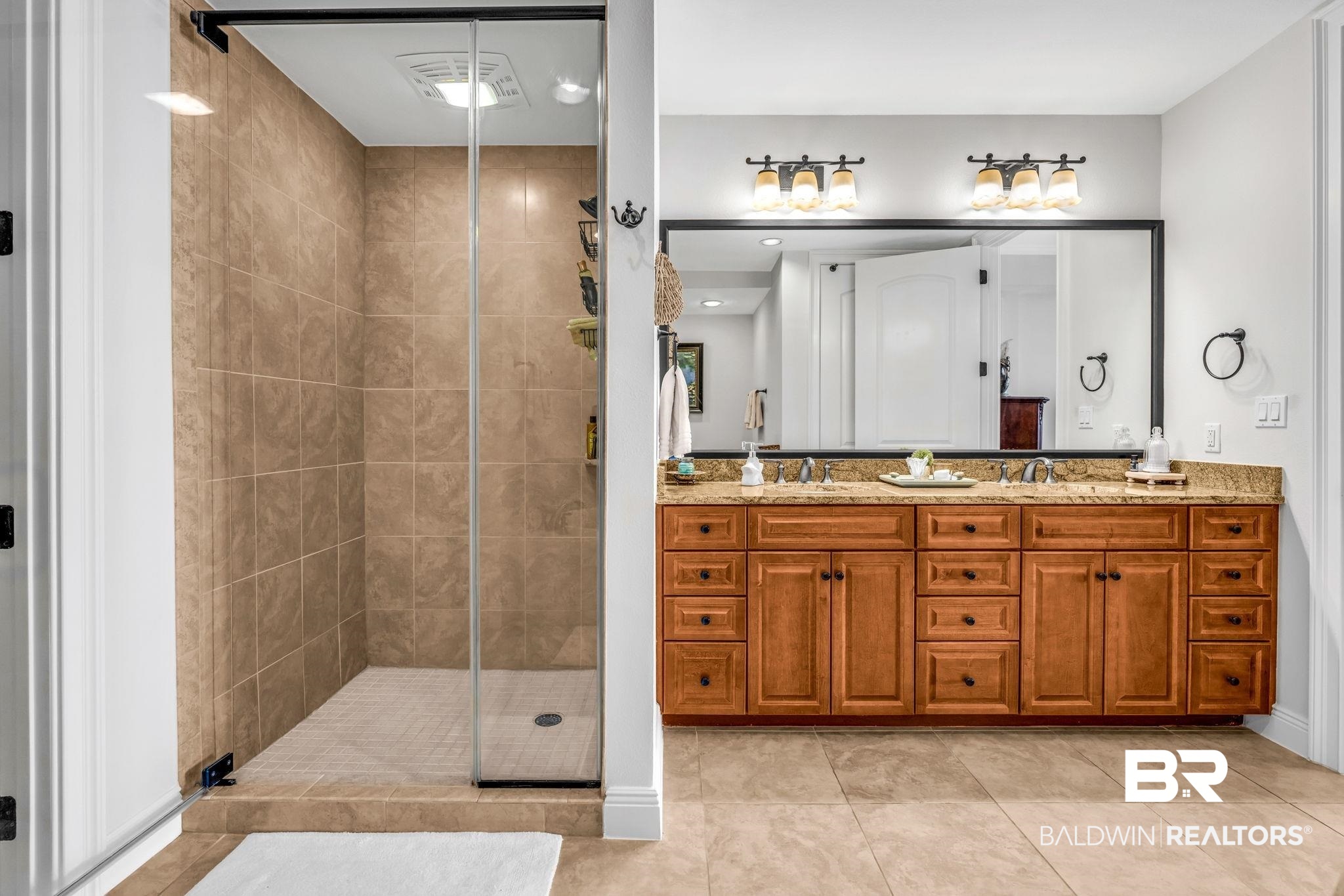 14500 River Road, Unit 305 Pensacola, FL 32507 - Photo 19 of 42 Tiled walk-in shower with a glass enclosure, accompanied by a dual vanity featuring light wood cabinetry, a granite-finish countertop, and two vessel sinks under a large framed mirror