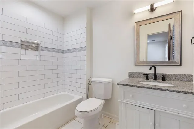 a bathroom with a granite countertop sink a toilet and bathtub