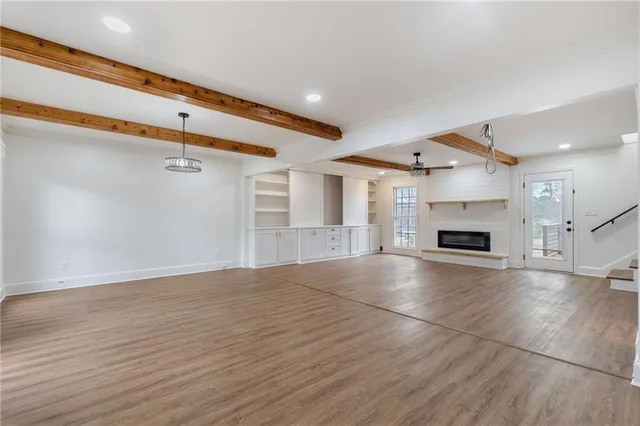 an empty room with wooden floor fireplace and windows