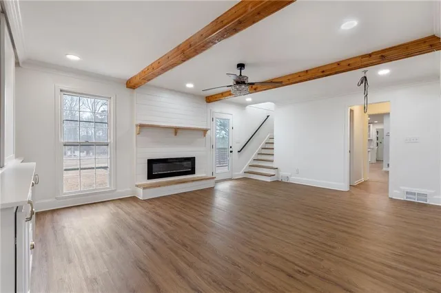 an empty room with wooden floor fireplace and windows