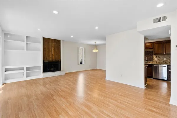 a view of an empty room with kitchen window and a refrigerator