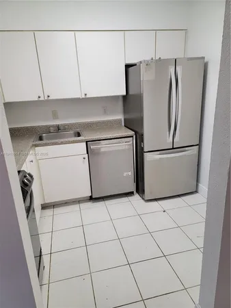a kitchen with a refrigerator and white cabinets