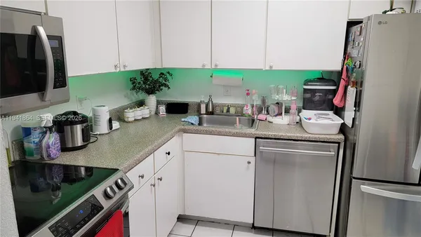 a kitchen with stainless steel appliances white cabinets sink and a refrigerator