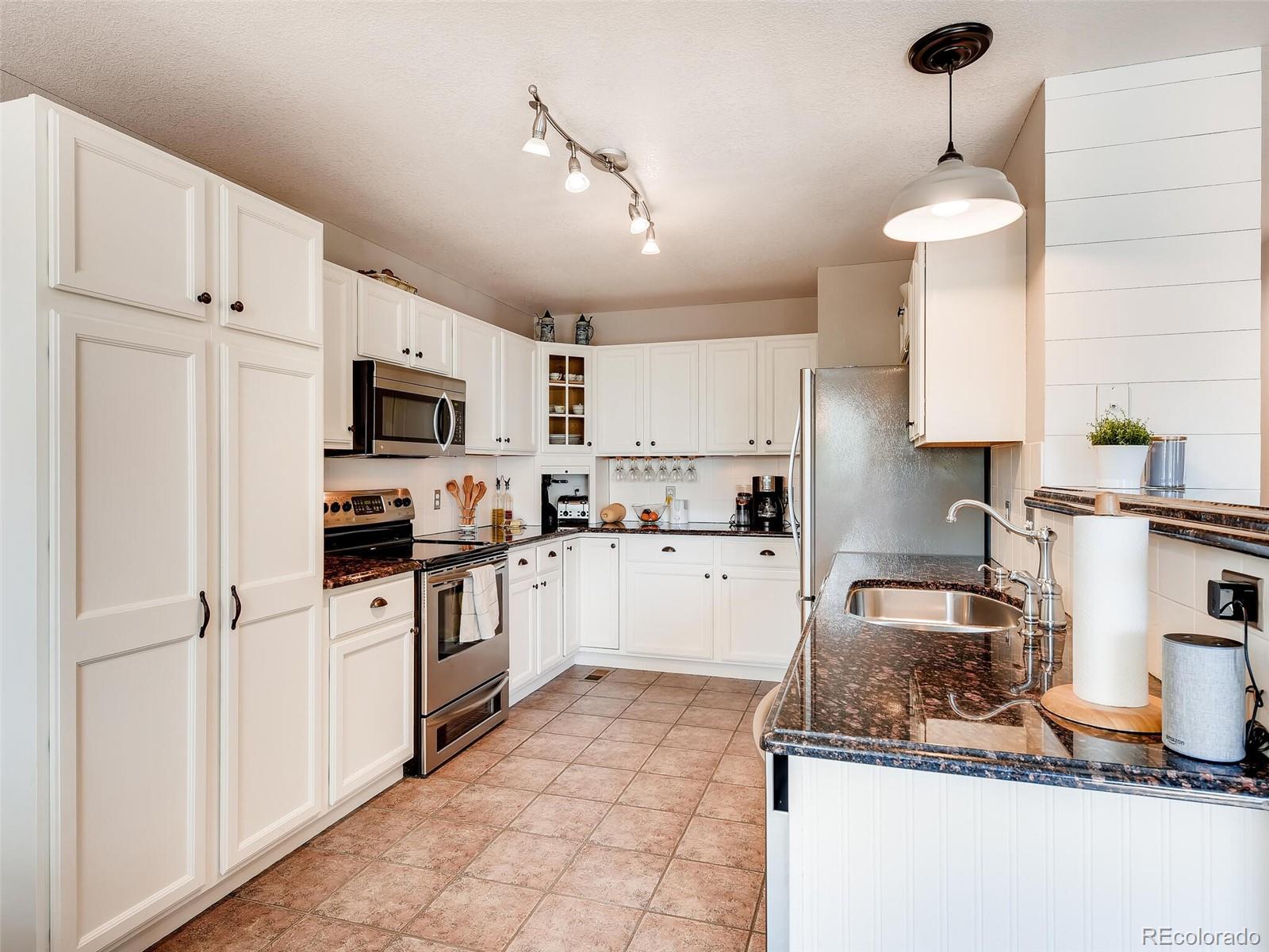 2373 Hyacinth Road Highlands Ranch, CO 80129 - Photo 3 of 38 a kitchen with granite countertop a sink stainless steel appliances and white cabinets