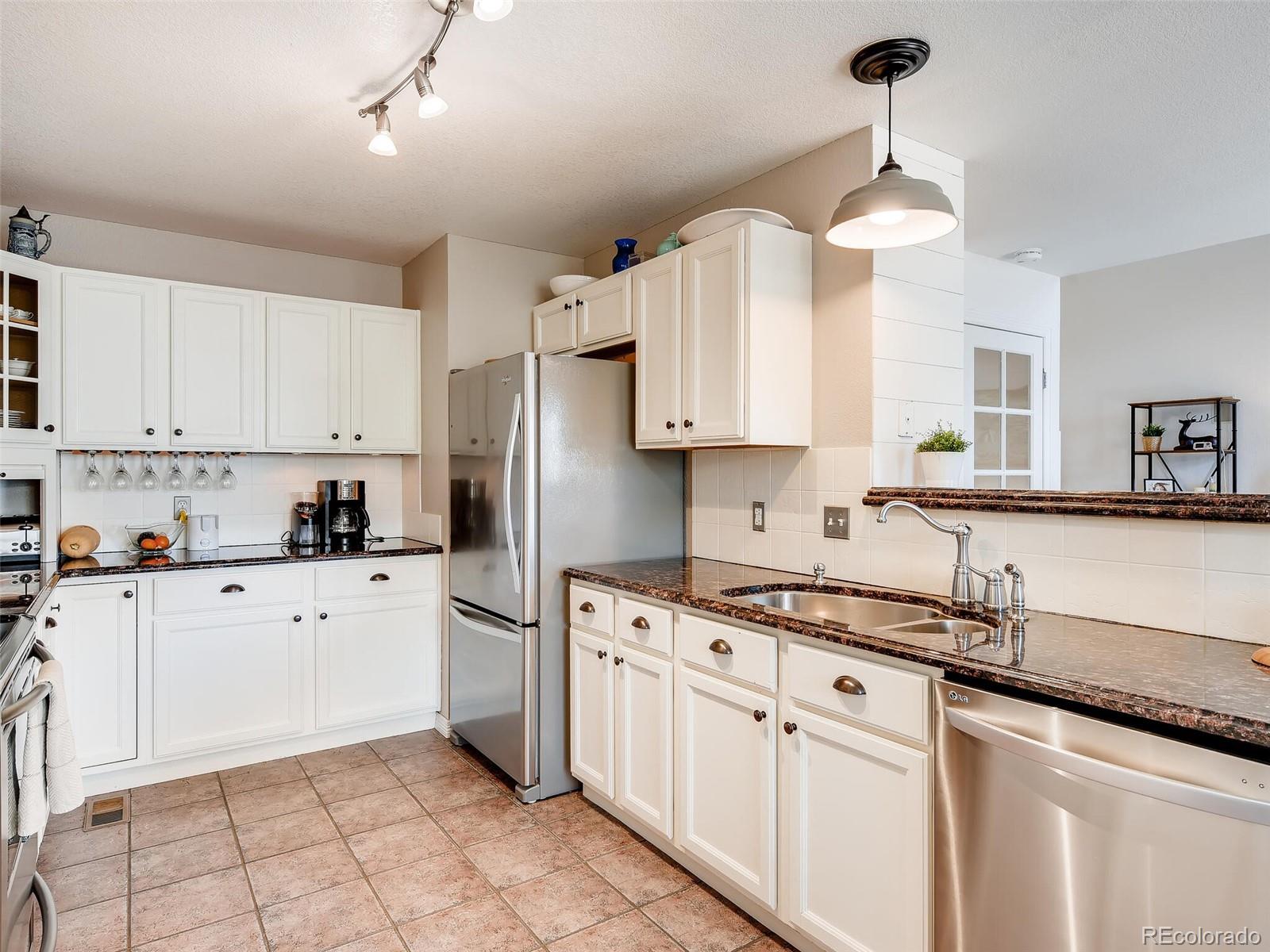 2373 Hyacinth Road Highlands Ranch, CO 80129 - Photo 4 of 38 a kitchen with white cabinets and white appliances