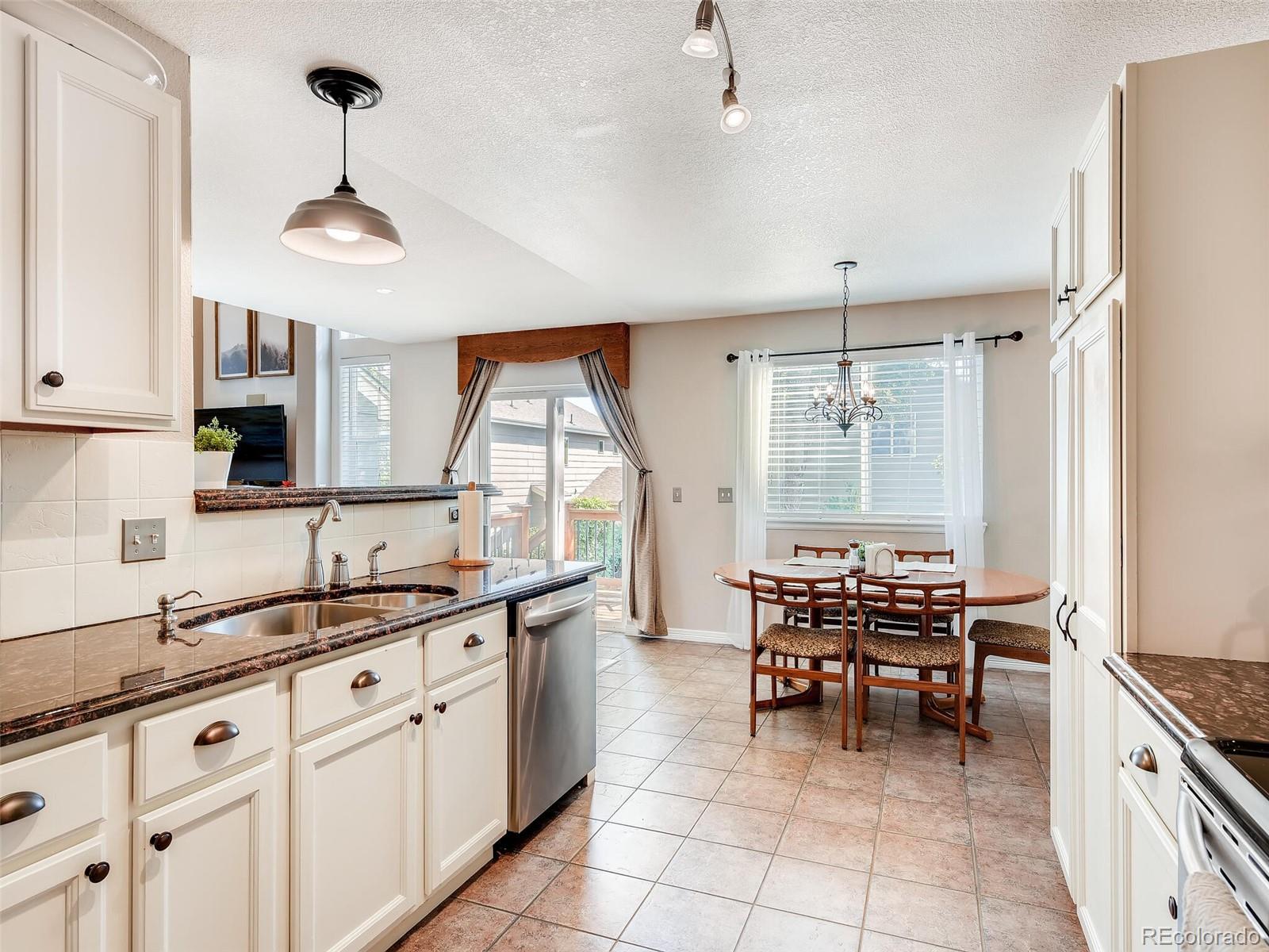 2373 Hyacinth Road Highlands Ranch, CO 80129 - Photo 5 of 38 a kitchen with granite countertop a sink stainless steel appliances and chairs