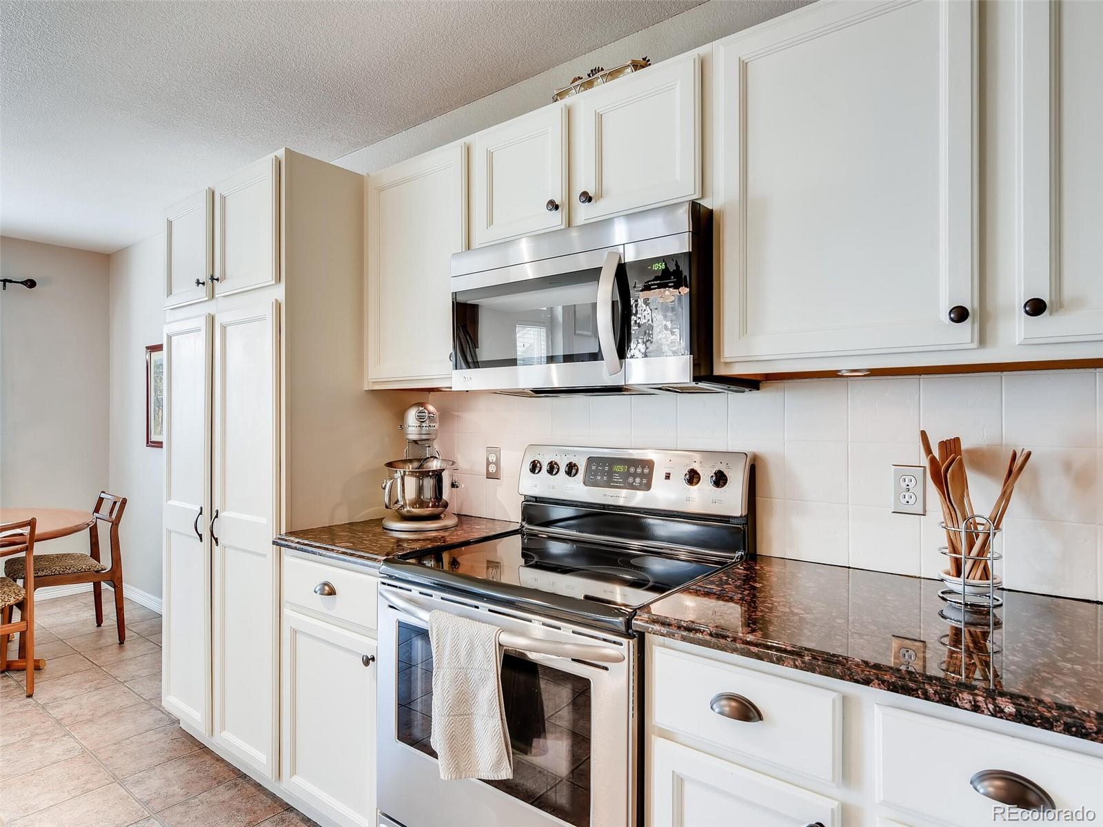 2373 Hyacinth Road Highlands Ranch, CO 80129 - Photo 6 of 38 a kitchen with stainless steel appliances granite countertop white cabinets a stove a sink and dishwasher