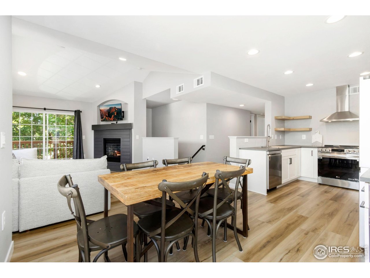 a open dining room with stainless steel appliances kitchen island granite countertop a dining table chairs and a refrigerator