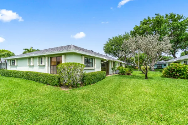 a view of a house with a big yard plants and large trees