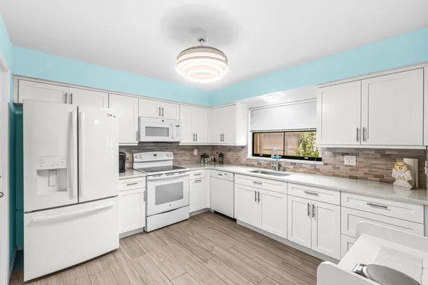 a kitchen with white cabinets white appliances and sink