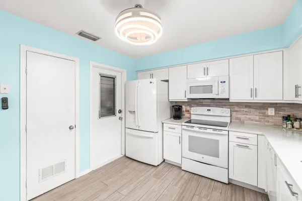 a kitchen with white cabinets and white appliances