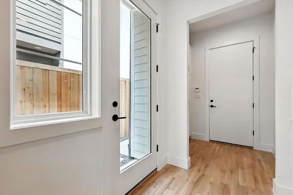 a view of an empty room with wooden floor and a window