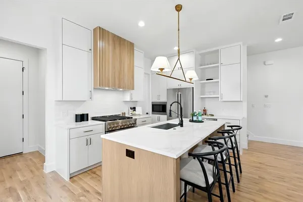 a kitchen with stainless steel appliances granite countertop a stove a sink dishwasher and a refrigerator with wooden floor