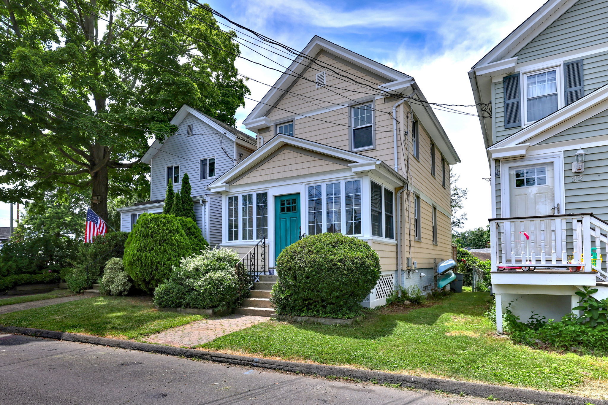 a view of a brick house with a yard plants and large tree