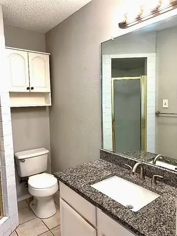a bathroom with a granite countertop toilet sink and mirror