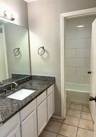 a bathroom with a granite countertop sink a mirror and a bathtub