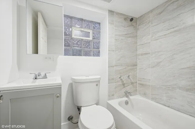 a bathroom with a toilet sink vanity tub and mirror