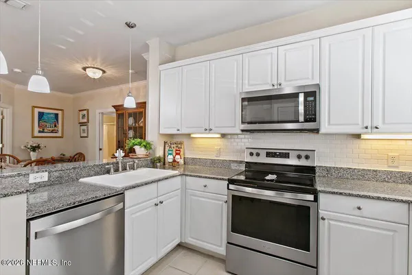 a kitchen with granite countertop white cabinets white stainless steel appliances and a sink