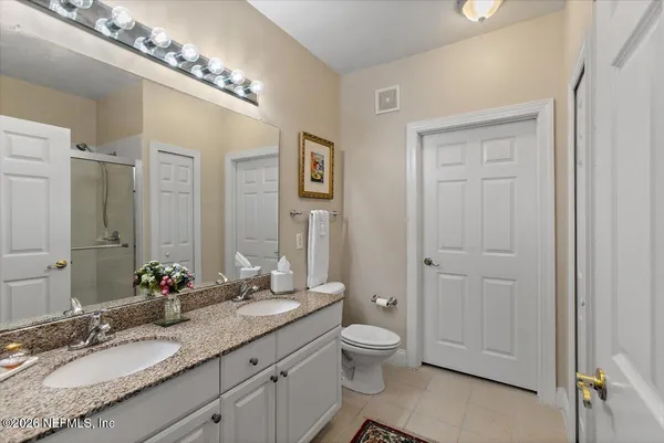 a bathroom with a granite countertop sink a toilet and a mirror