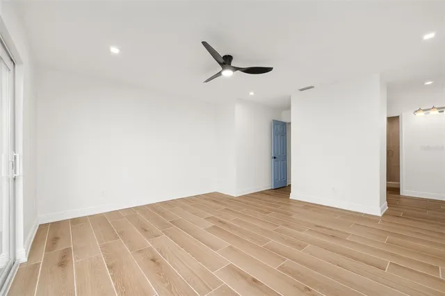 an empty room with wooden floor and windows