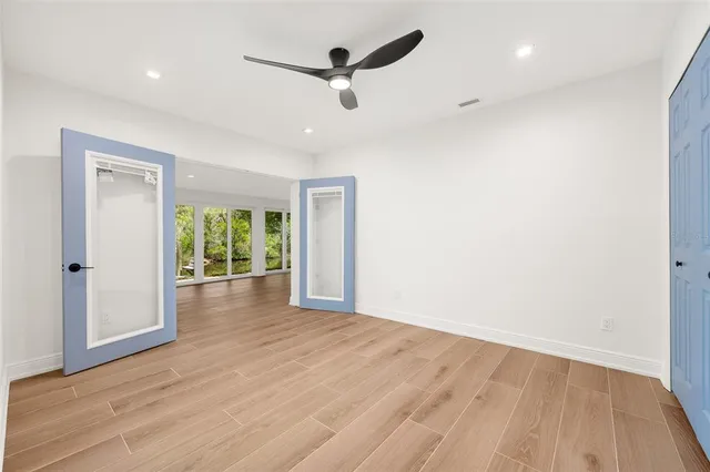 a view of empty room with wooden floor and fan