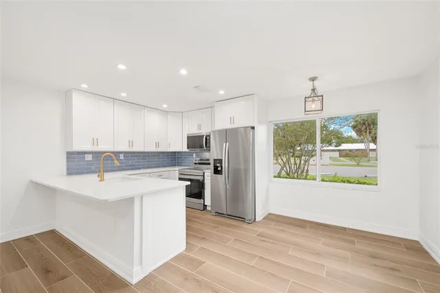 a kitchen with a refrigerator a stove a microwave and a window