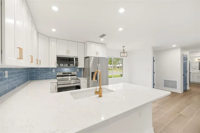 a kitchen with stainless steel appliances a refrigerator sink stove microwave and cabinets