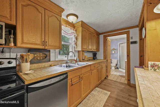a kitchen with stainless steel appliances granite countertop a stove a sink dishwasher and cabinets with wooden floor