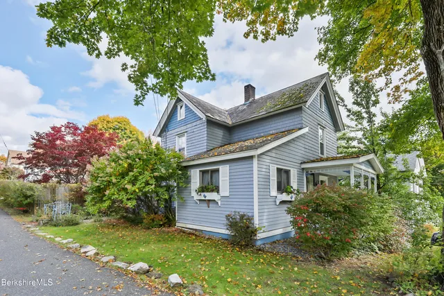 a front view of a house with a garden and tree