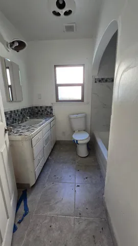 a bathroom with a granite countertop toilet sink and mirror
