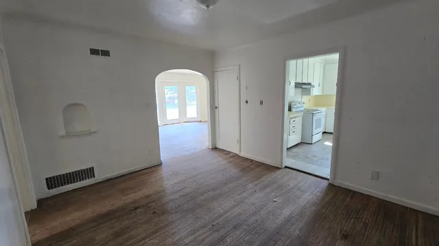 an empty room with wooden floor and windows