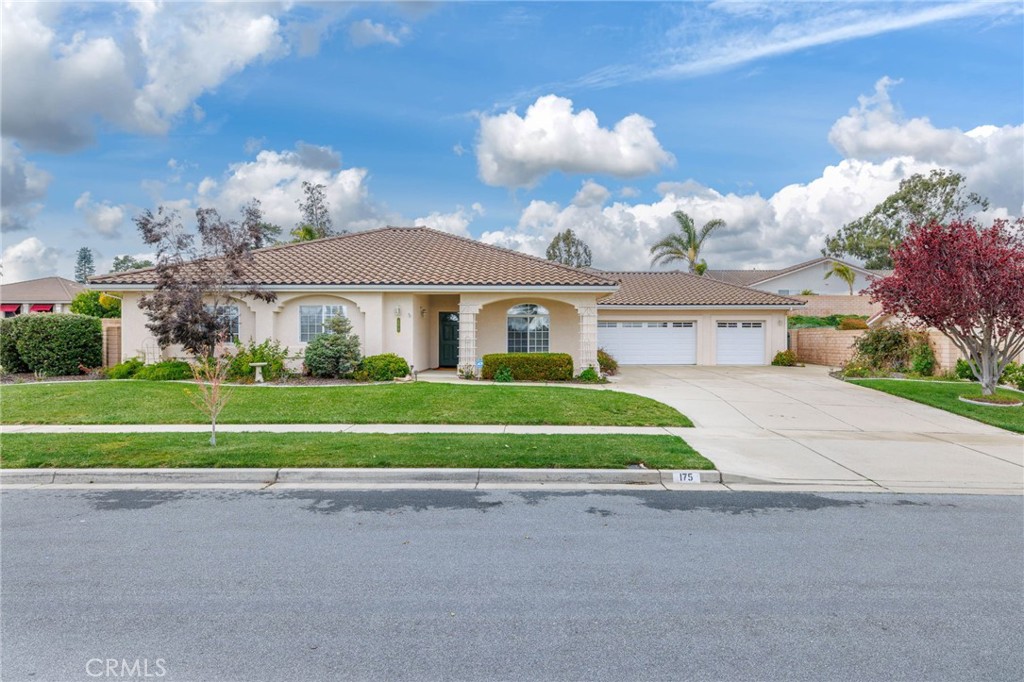 a view of a white house with a big yard and potted plants