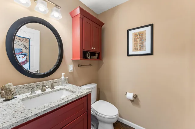 a bathroom with a granite countertop toilet a sink and a mirror