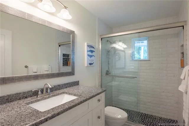 a bathroom with a granite countertop sink toilet a mirror a vanity and shower