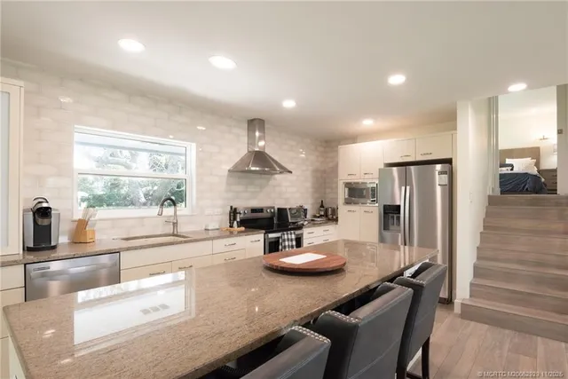 a kitchen with stainless steel appliances granite countertop a sink refrigerator and cabinets