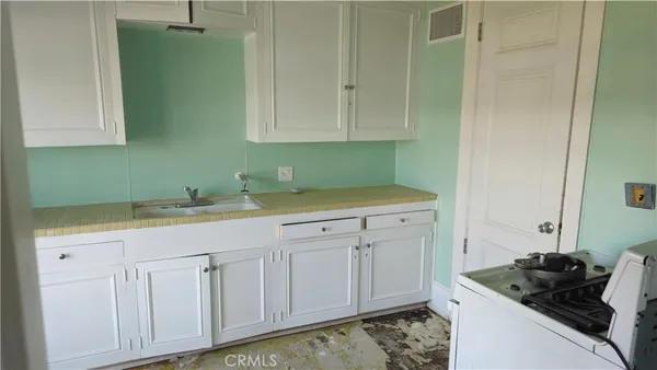 a kitchen with white cabinets and sink