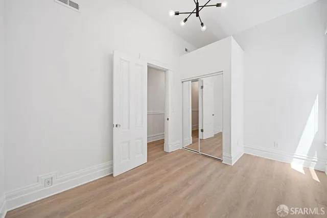 an empty room with wooden floor and ceiling fan