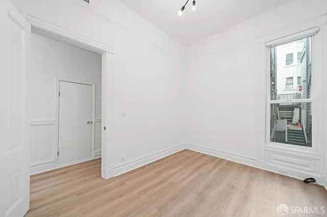 a view of empty room with wooden floor and fan