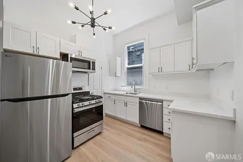 a kitchen with stainless steel appliances a refrigerator a stove a sink and white cabinets