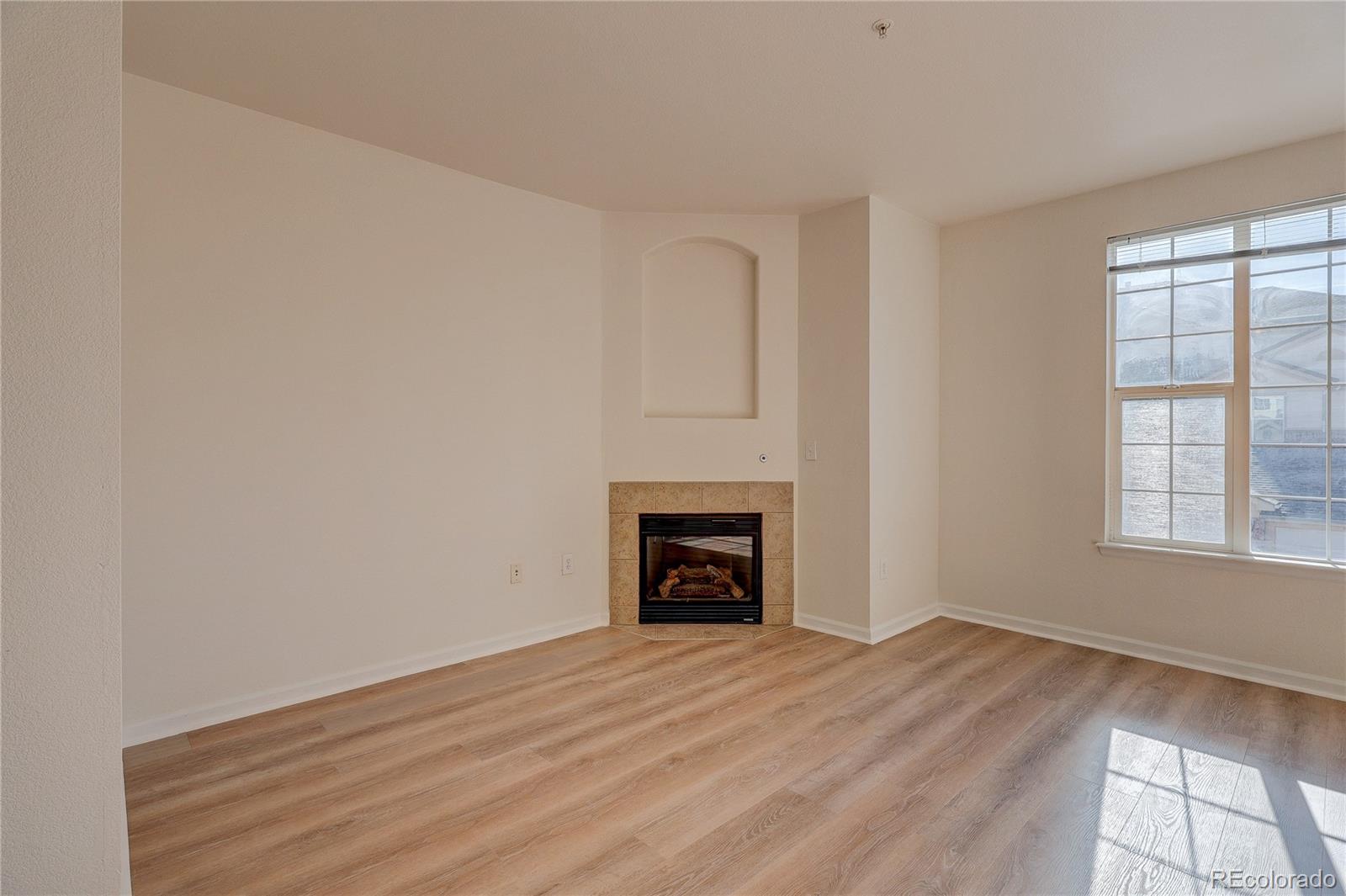 5756 North Genoa Way, Unit 12208 Aurora, CO 80019 - Photo 5 of 33 an empty room with wooden floor fireplace and windows