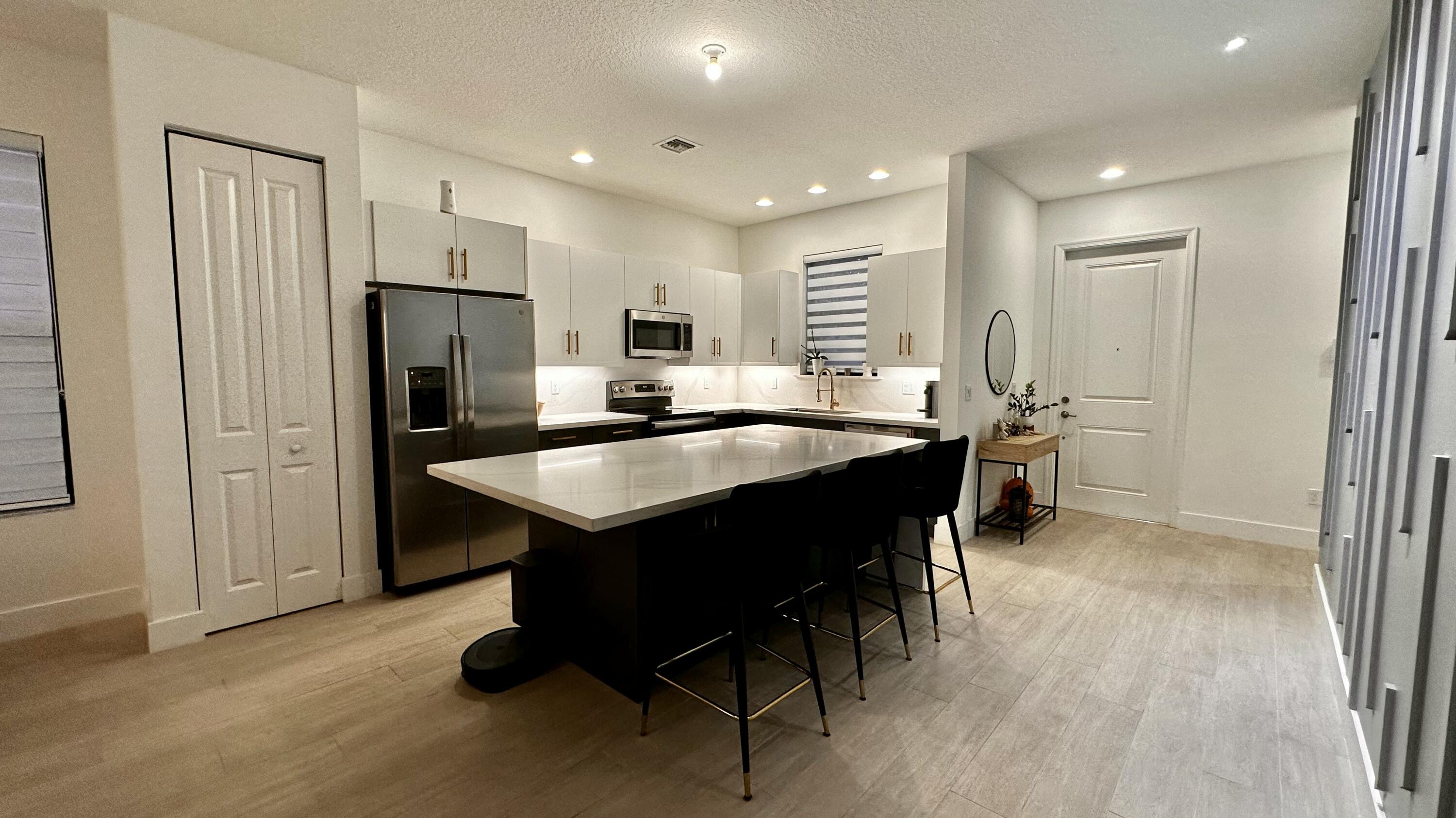 5570 Quiet Lake Place Westlake, FL 33470 - Photo 6 of 18 a kitchen with stainless steel appliances kitchen island granite countertop a refrigerator a sink a stove a dining table and chairs