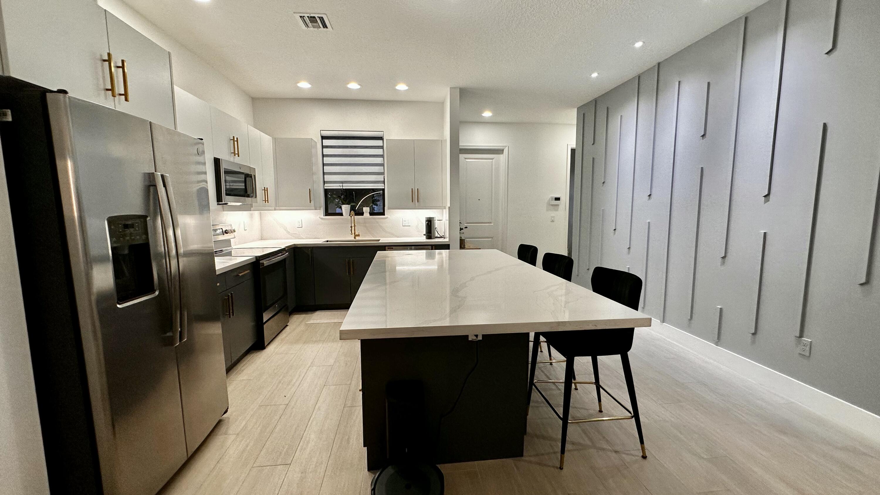 5570 Quiet Lake Place Westlake, FL 33470 - Photo 7 of 18 a kitchen with stainless steel appliances a refrigerator a sink dishwasher a stove and white cabinets with wooden floor